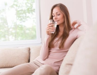 Woman sitting on a sofa drinking a glass of water